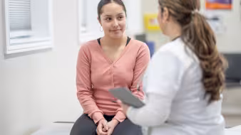 Latina teenager in medical office with clinician