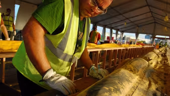 A man in a high-visibility jacket and gloves at work