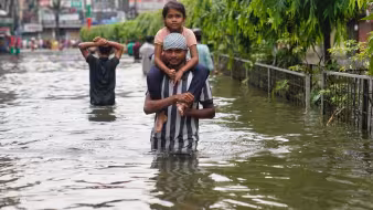 A father carrying his child through floodwater in Bangladesh