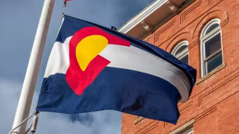 Colorado flag in front of a brick building