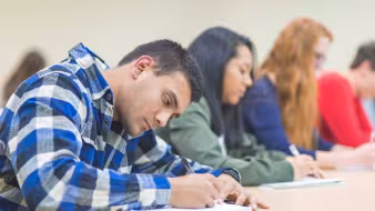 A multiethnic classroom of university students sit at their desks
