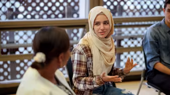 A college student in a hijab talks to another woman