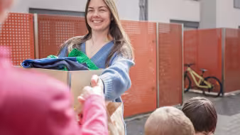 A Ukrainian woman receives a box of donated clothes from a European woman