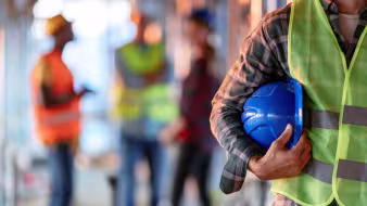 Construction worker holding a blue hard hat.