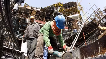 A migrant worker cuts through a metal rod at a construction site in Qatar