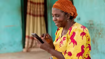 A woman in Nigeria smiles while using her mobile phone