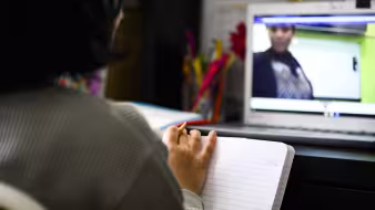 A girl sits facing a laptop, where she watches her teacher as part of virtual classes during the COVID-19 pandemic
