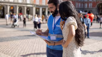 Volunteer talks to woman and writes on a clipboard in Madrid