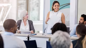 Young woman speaks to other participants at a meeting
