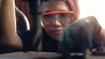 A young woman operating an industrial drilling machine