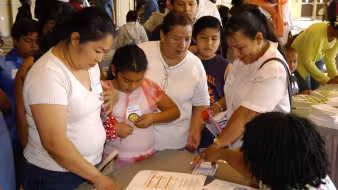Parents and their children talk to another adult seated at a table at a Parents & Family Conference