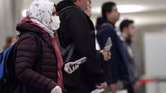 Travelers arrive at a U.S. airport wearing masks during the COVID-19 pandemic