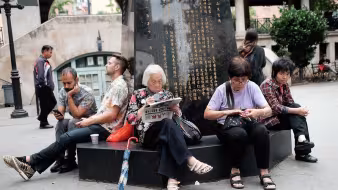 Group of people sit in a park in New York's Chinatown