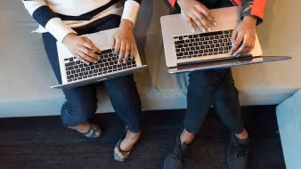 Two women use their laptops