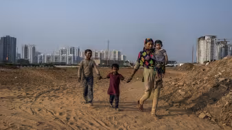 An Indian internal migrant walks with her children in Delhi