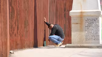 A man says goodbye to his partner through the border fence