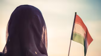 A woman holding an Iranian flag at sunset.