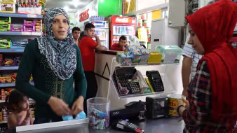 A Syrian refugee woman uses a special e-card to purchase food at a grocery store in Turkey. 