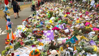 People pass by flowers laying on a street
