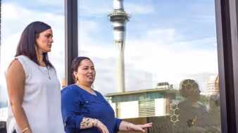 Women walk by the Sky Tower in Auckland.