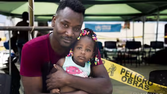 A Haitian man hugs his daughter in Peru.