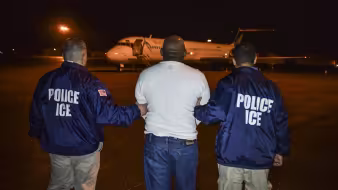 A migrant scheduled to be deported from the United States is escorted to a charter flight. 