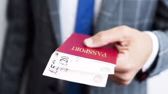 A man presents cash inside a passport