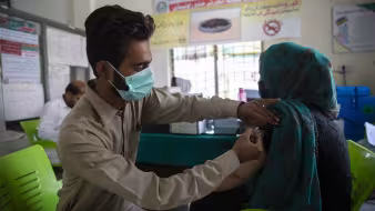 An Afghan refugee receives a COVID-19 vaccination in Pakistan.
