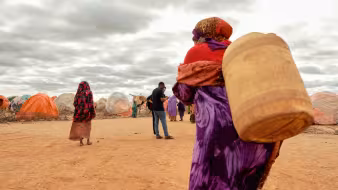 A displaced woman walks with a jerrycan of water in Somalia.