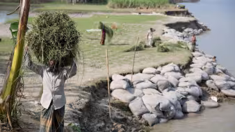 A man walks through a community affected by river erosion in Bangladesh.