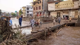 People cross a bridge in the middle of a flooded city in Pakistan.