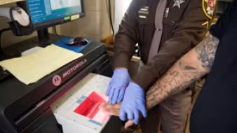 An office checks arrestees' fingerprints against criminal and immigration databases.