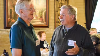 Two men talk during a retiree luncheon