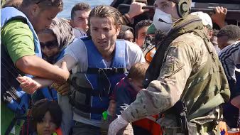 Sailors and marines on the HMS Bulwark help migrants ashore in Italy.