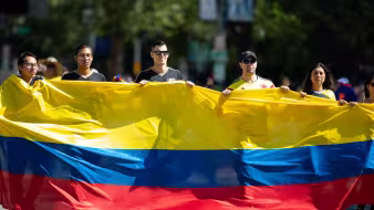 Varias personas portan una bandera gigante de Colombia en un desfile en Washington, DC.