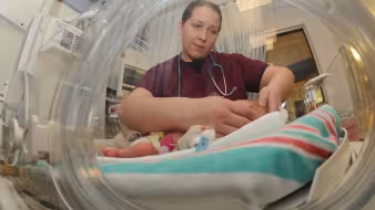 An intern examines a newborn baby in the Neonatal Intensive Care Unit.