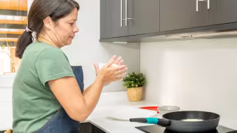 Una mujer prepara arepas en la cocina. 