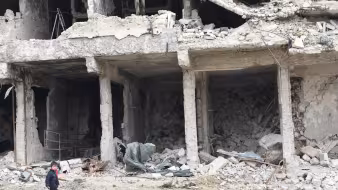A child walks by a destroyed building in Syria. 