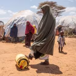 A woman rolls a jerrycan of water at a refugee camp in Kenya.